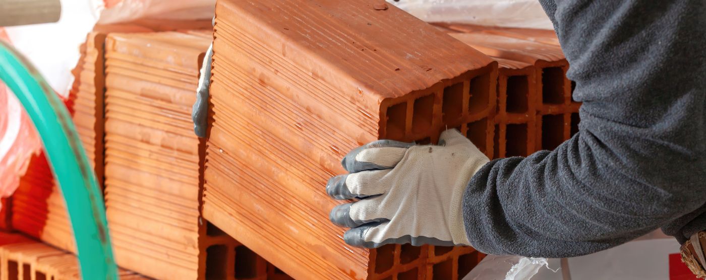 Trabajador manipulando ladrillos cerámicos con guantes